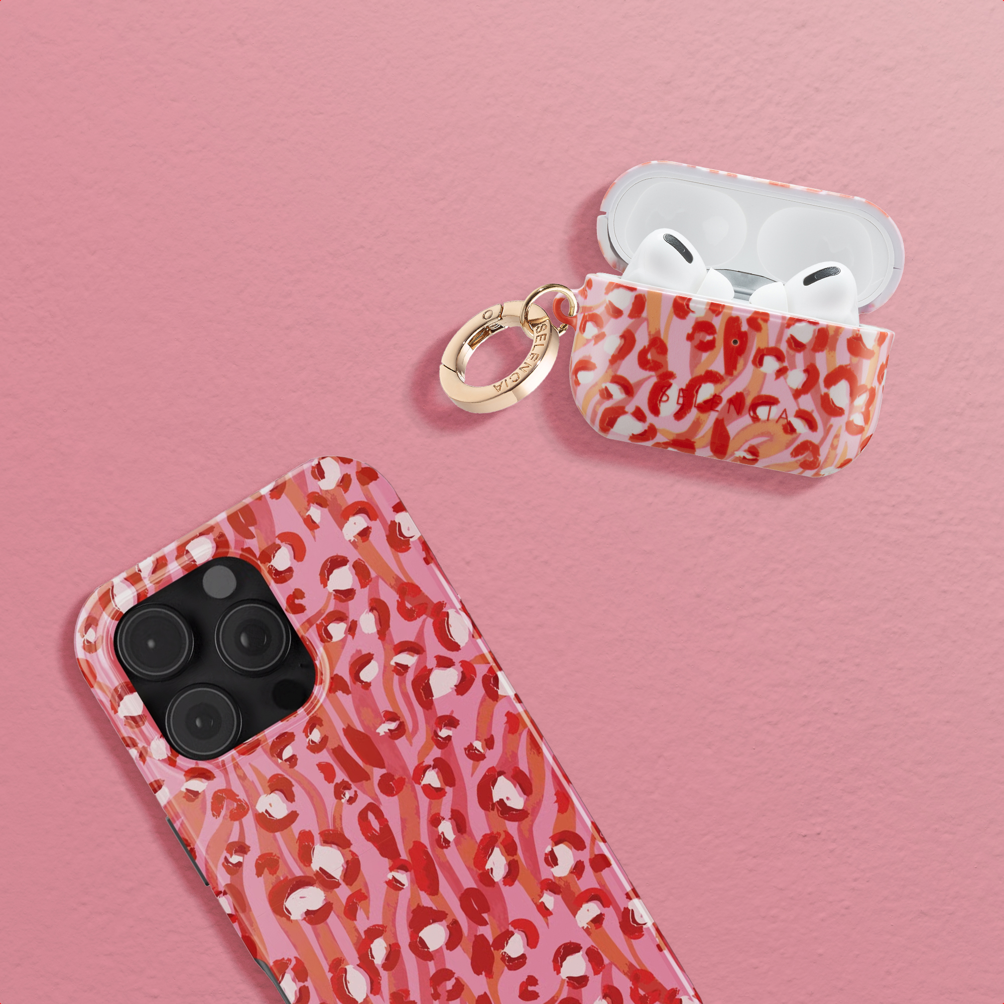Una funda de móvil rosa y una de AirPods Pro a juego con patrones rojos y blancos sobre fondo rosa.
