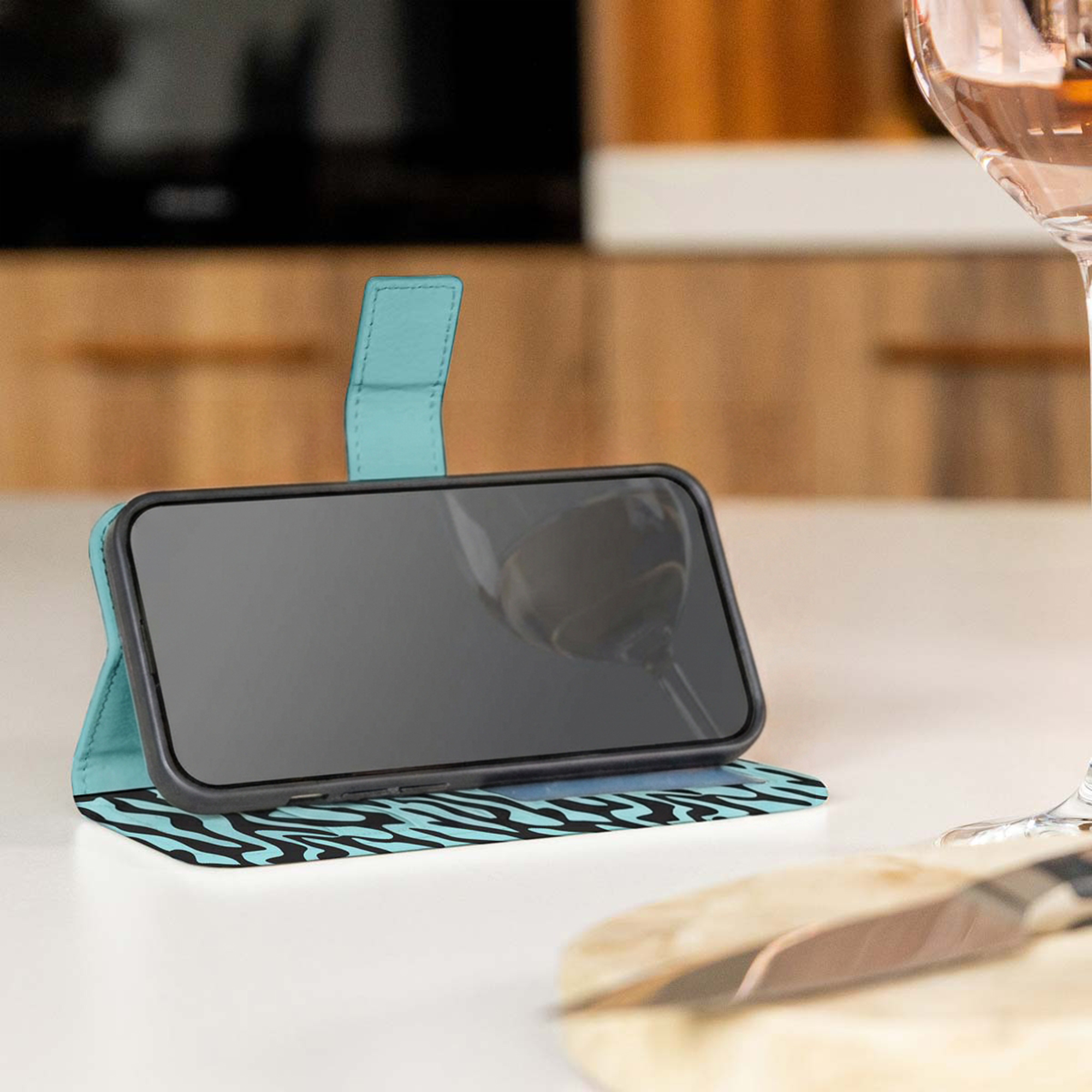 Un smartphone dans un étui bleu clair avec un imprimé tigre noir repose sur une table.