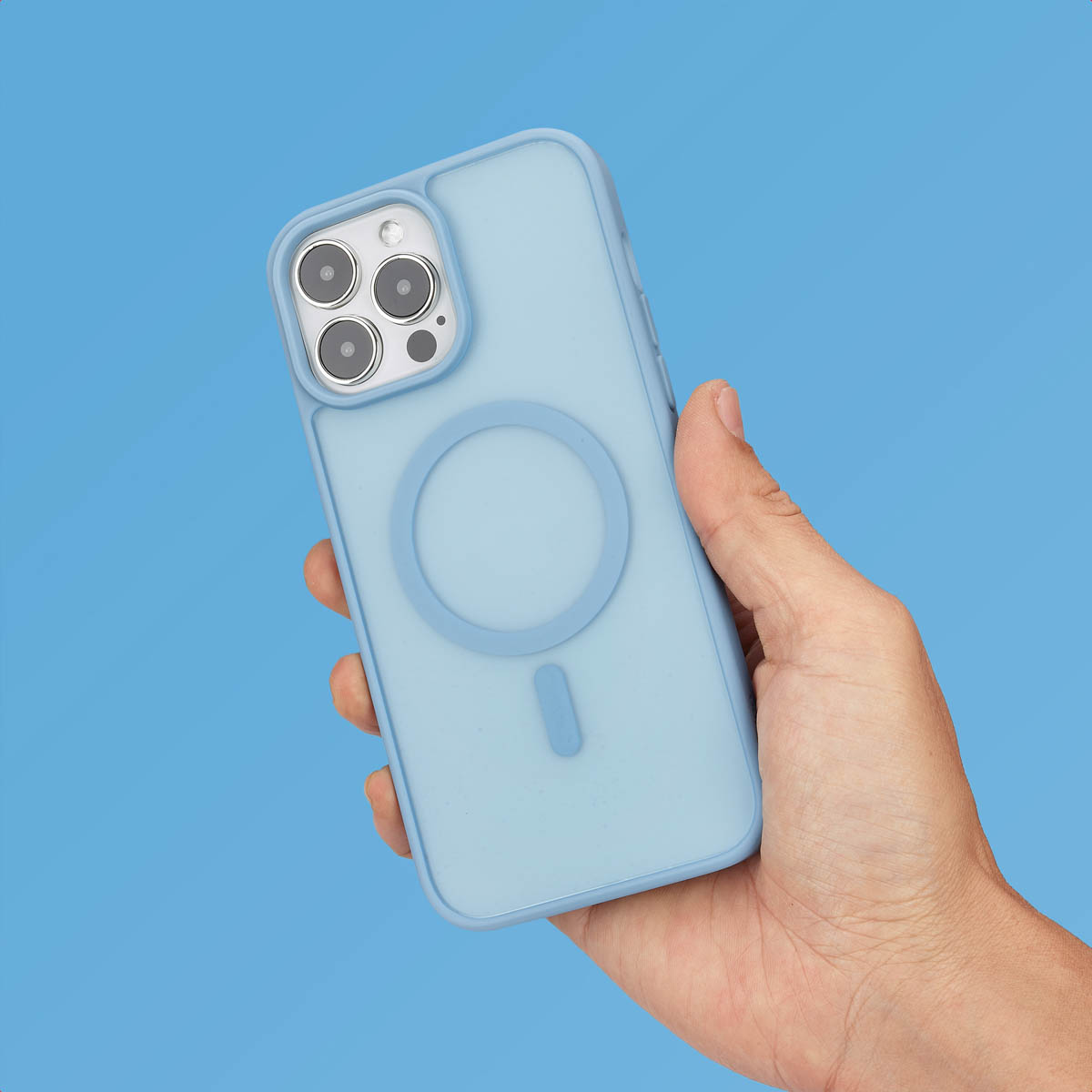 Une main tient un smartphone bleu clair avec une coque magnétique sur fond bleu.