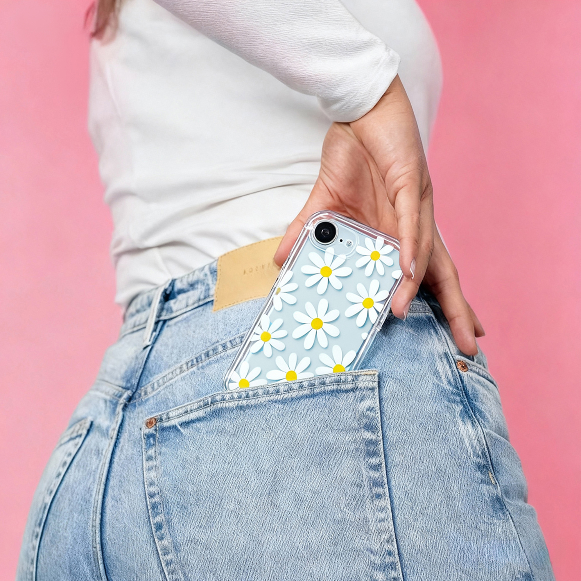 Une personne en jean bleu et haut blanc glisse un téléphone bleu à motif de marguerites dans sa poche arrière.