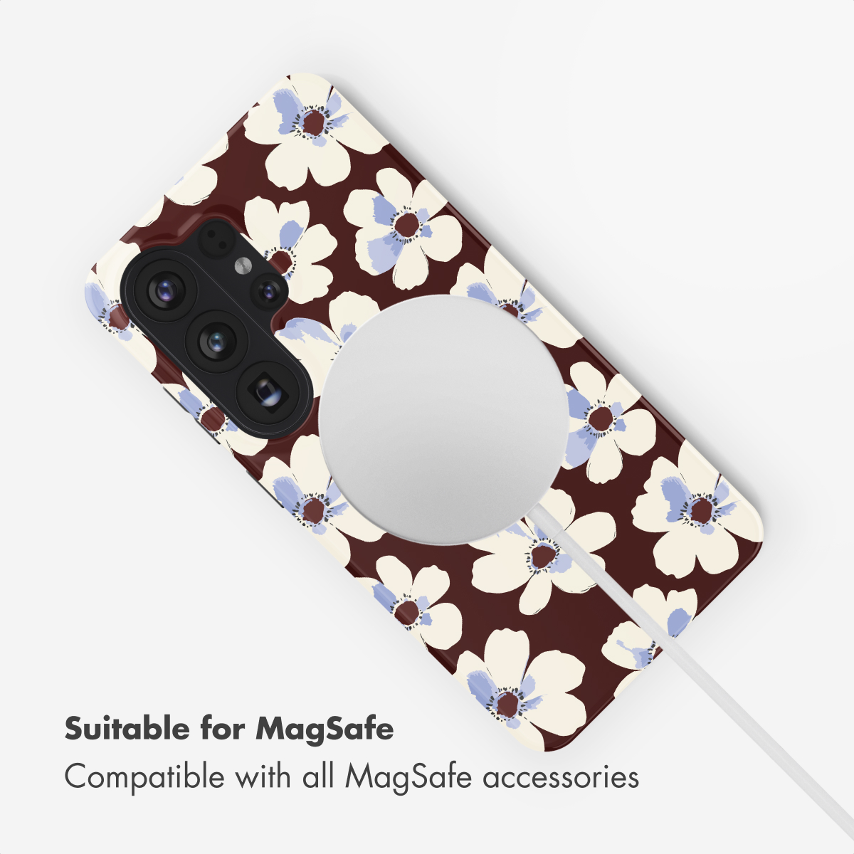 Handyhülle mit floralem Muster auf dunkelbraunem Grund und MagSafe-Ladegerät.