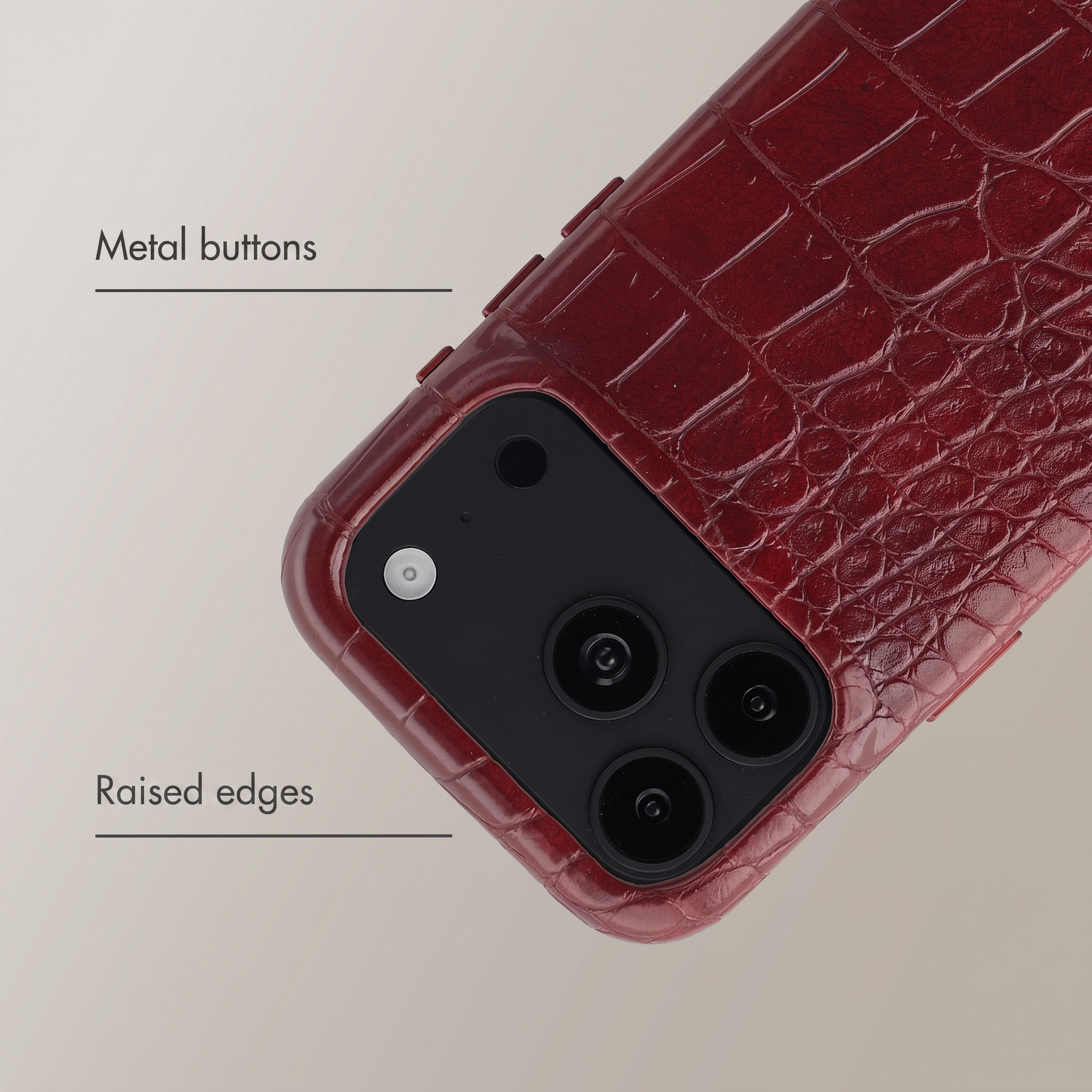 Custodia per telefono rossa in coccodrillo con bottoni metallici e bordi rialzati.