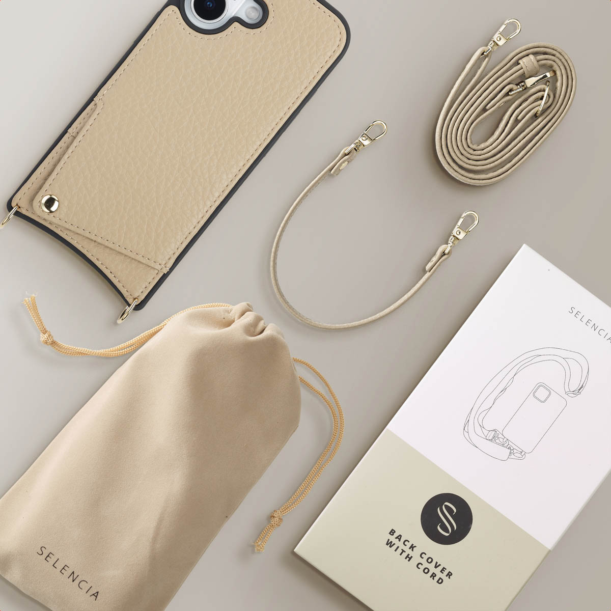 Funda de móvil beige con correa, lazo corto, bolsa de almacenamiento y caja en fondo claro.