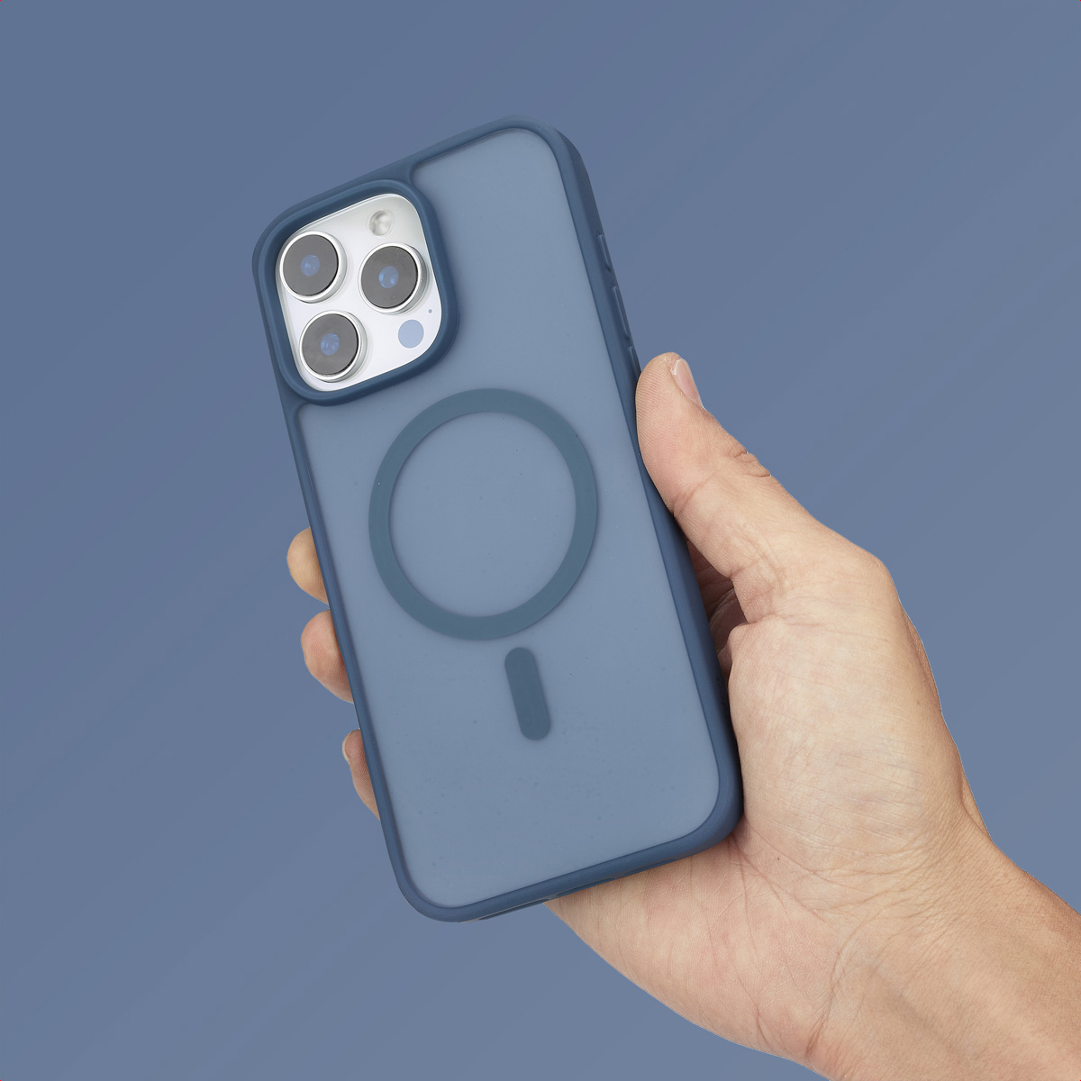 Una mano sostiene un smartphone azul con funda MagSafe sobre fondo azul.