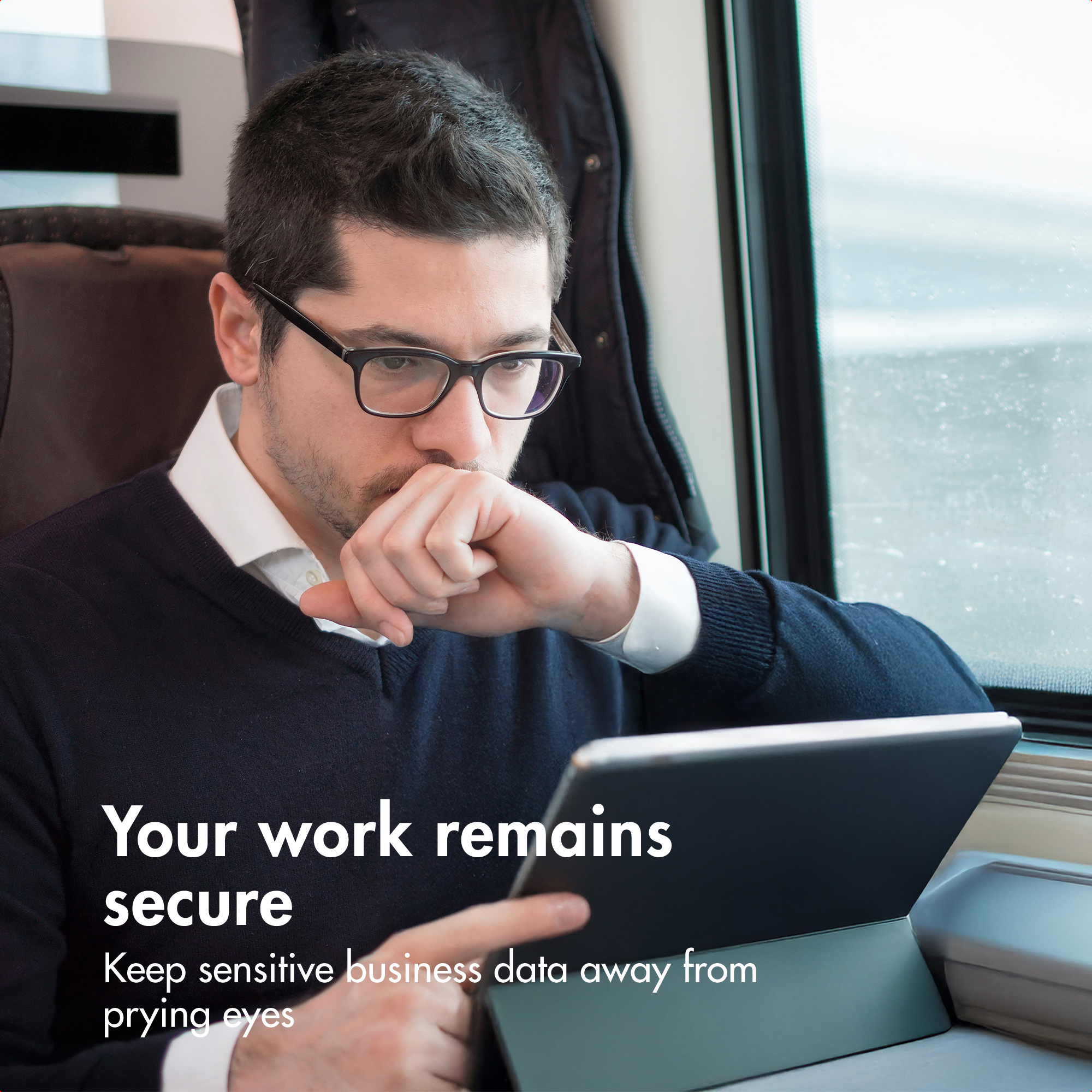 Un uomo con gli occhiali siede su un treno usando un laptop.