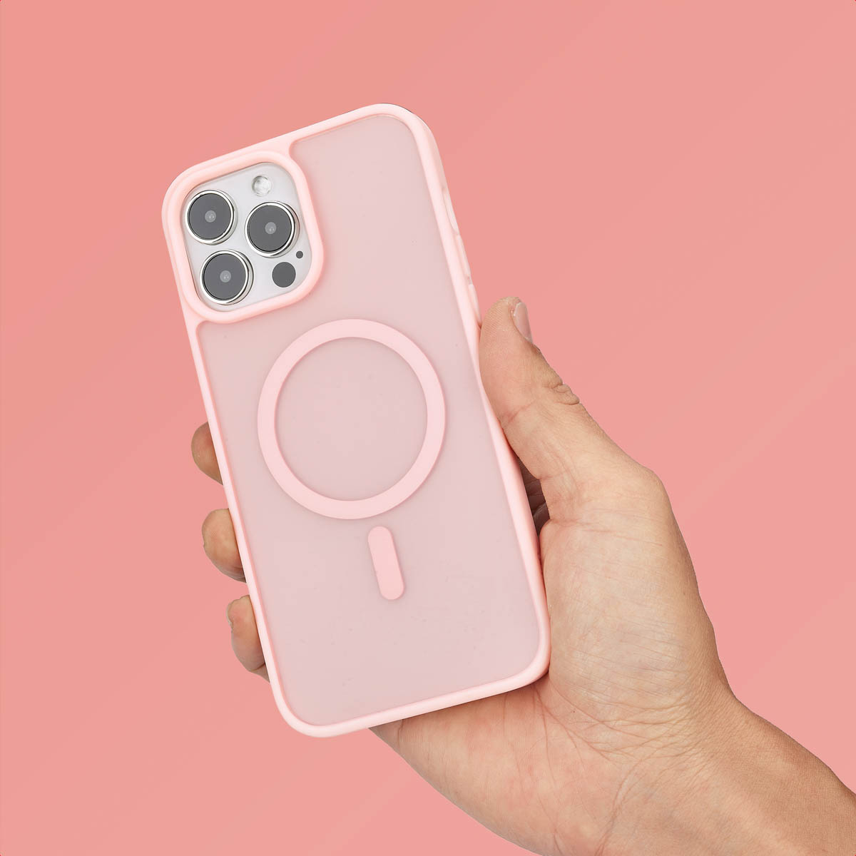 Een hand houdt een roze smartphone met hoesje vast tegen roze achtergrond.