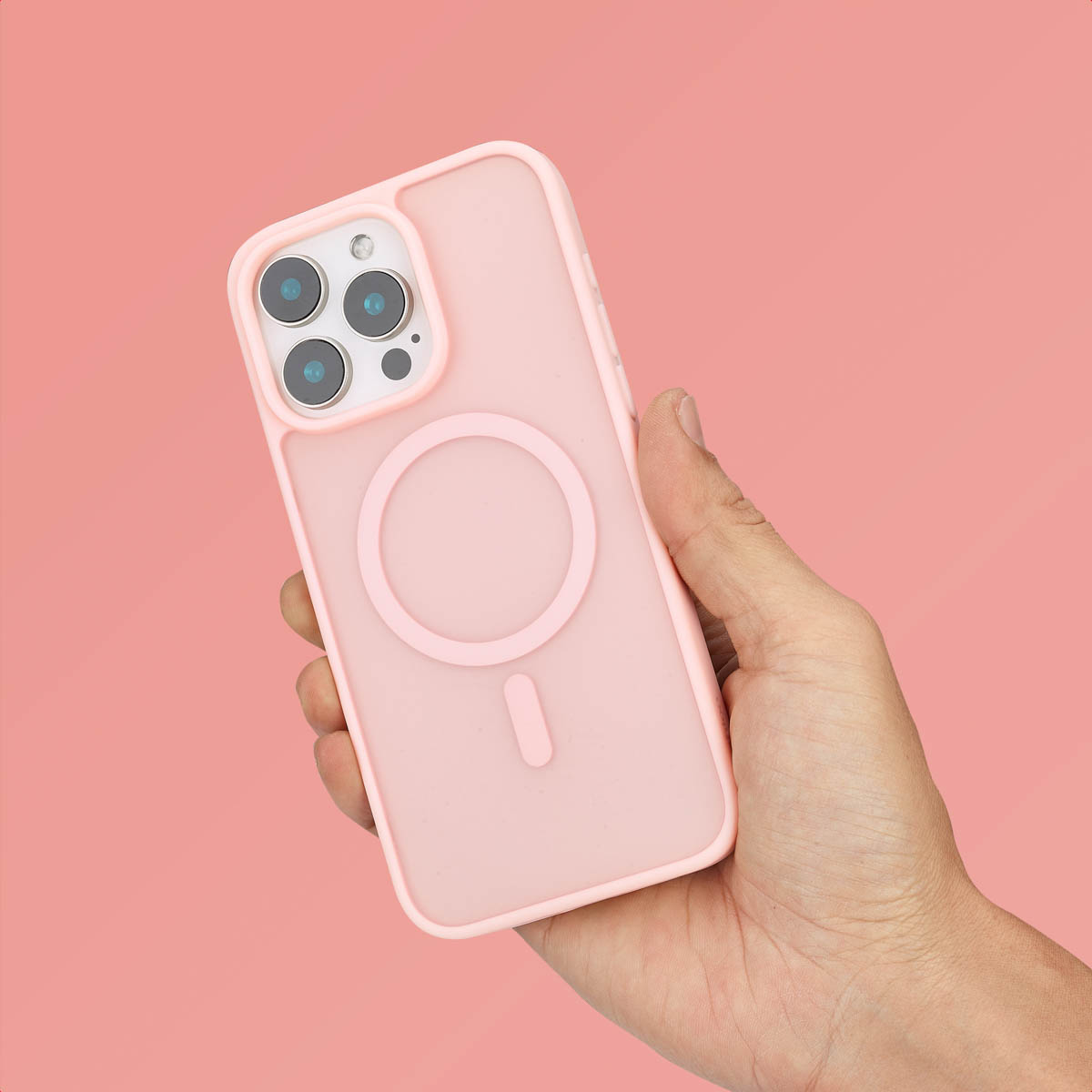 Een hand houdt een roze smartphone met een MagSafe hoesje tegen een roze achtergrond.