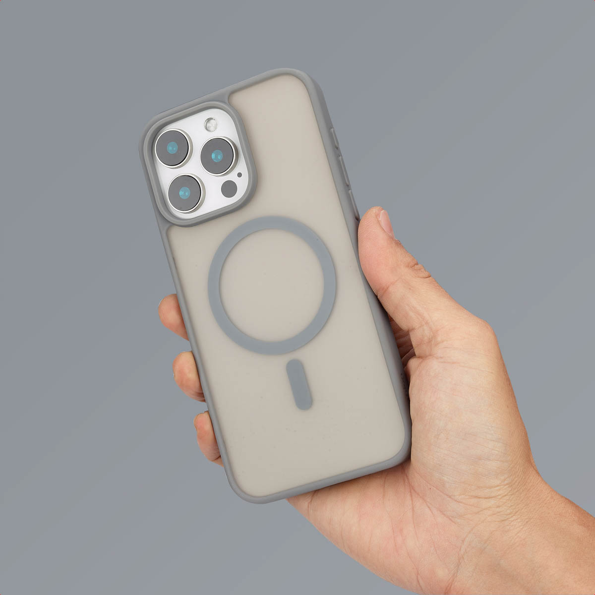 Une main tient une coque de smartphone gris givré avec un anneau MagSafe sur un fond gris.