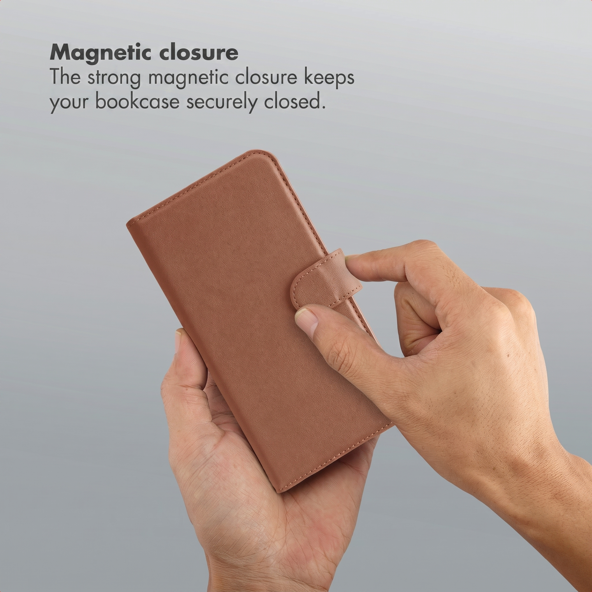 Hands holding a closed brown leather smartphone case with a magnetic closure.