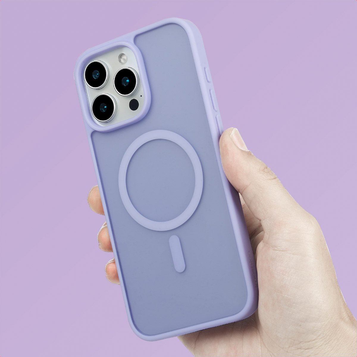 Una mano sostiene un smartphone morado claro con funda MagSafe sobre fondo morado.