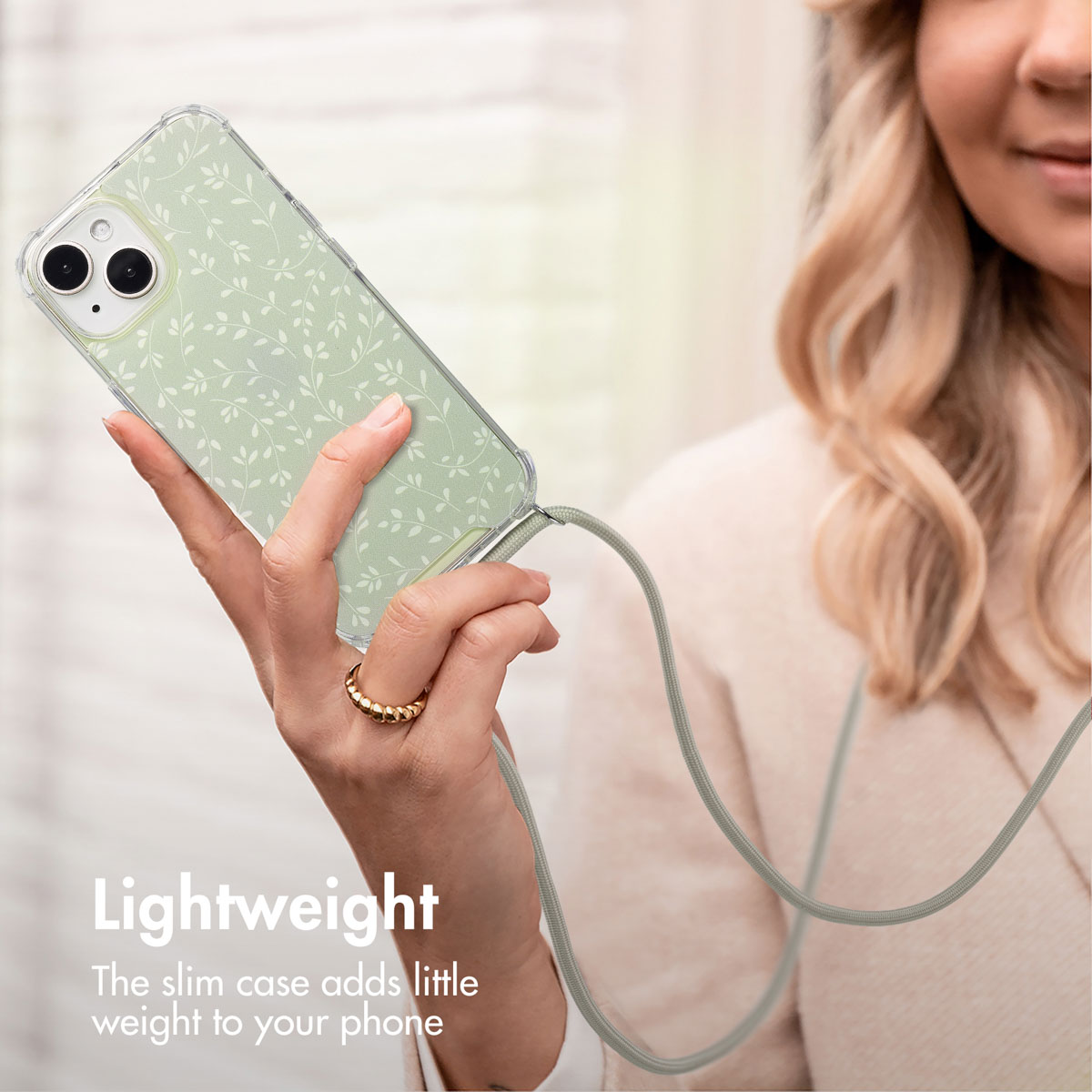 Una donna tiene un telefono con cover verde chiaro a foglie e laccetto coordinato.