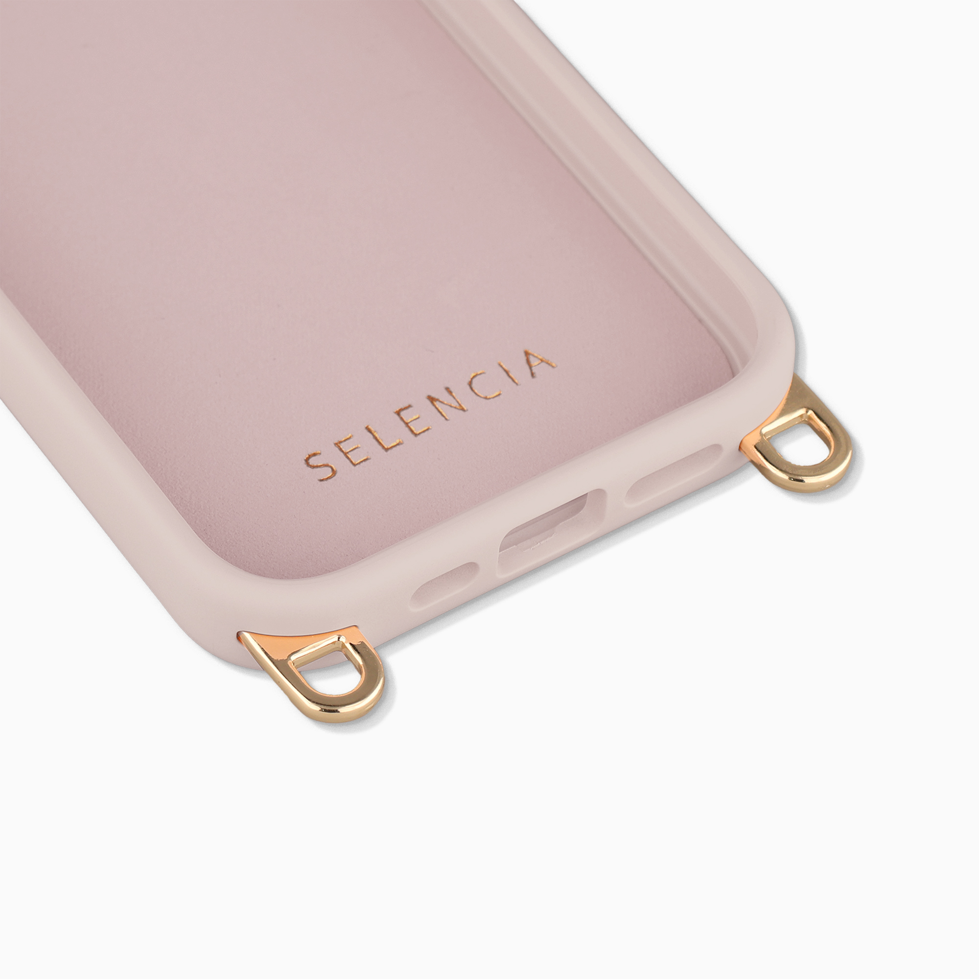 Gros plan d'une coque de téléphone rose pastel avec des anneaux en D dorés et la marque Selencia à l'intérieur sur fond blanc.