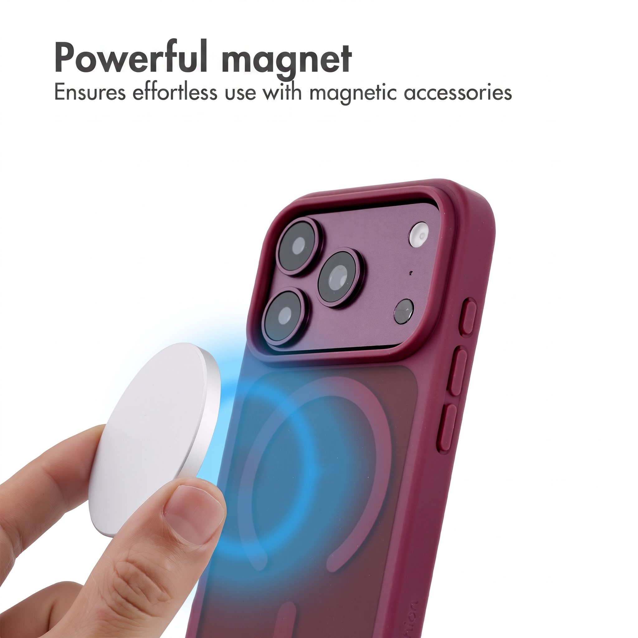 Una mano tiene un disco magnetico vicino a una cover per smartphone rosso scuro con anello MagSafe visibile.