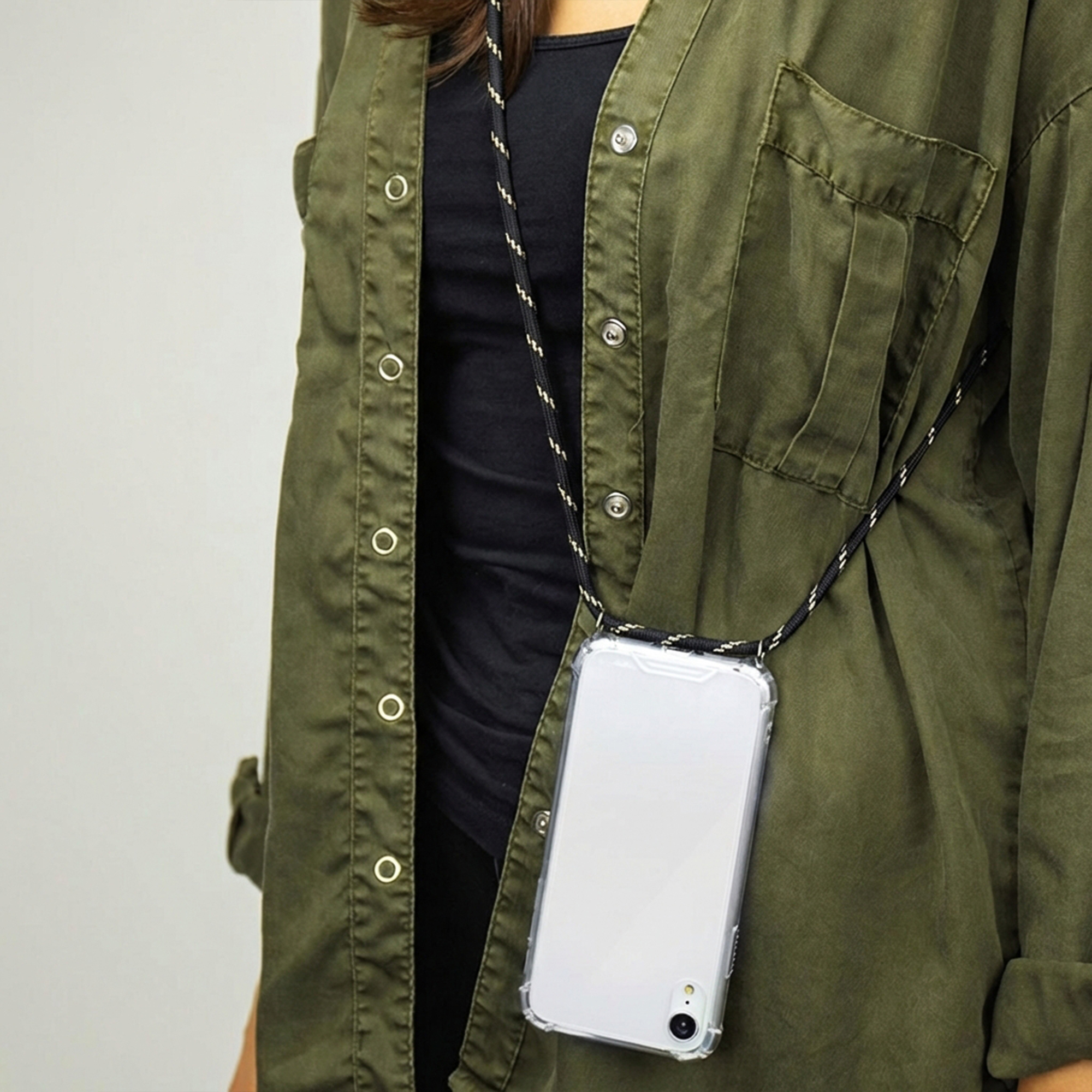 Persona con camisa verde lleva un smartphone en funda protectora con cordón.