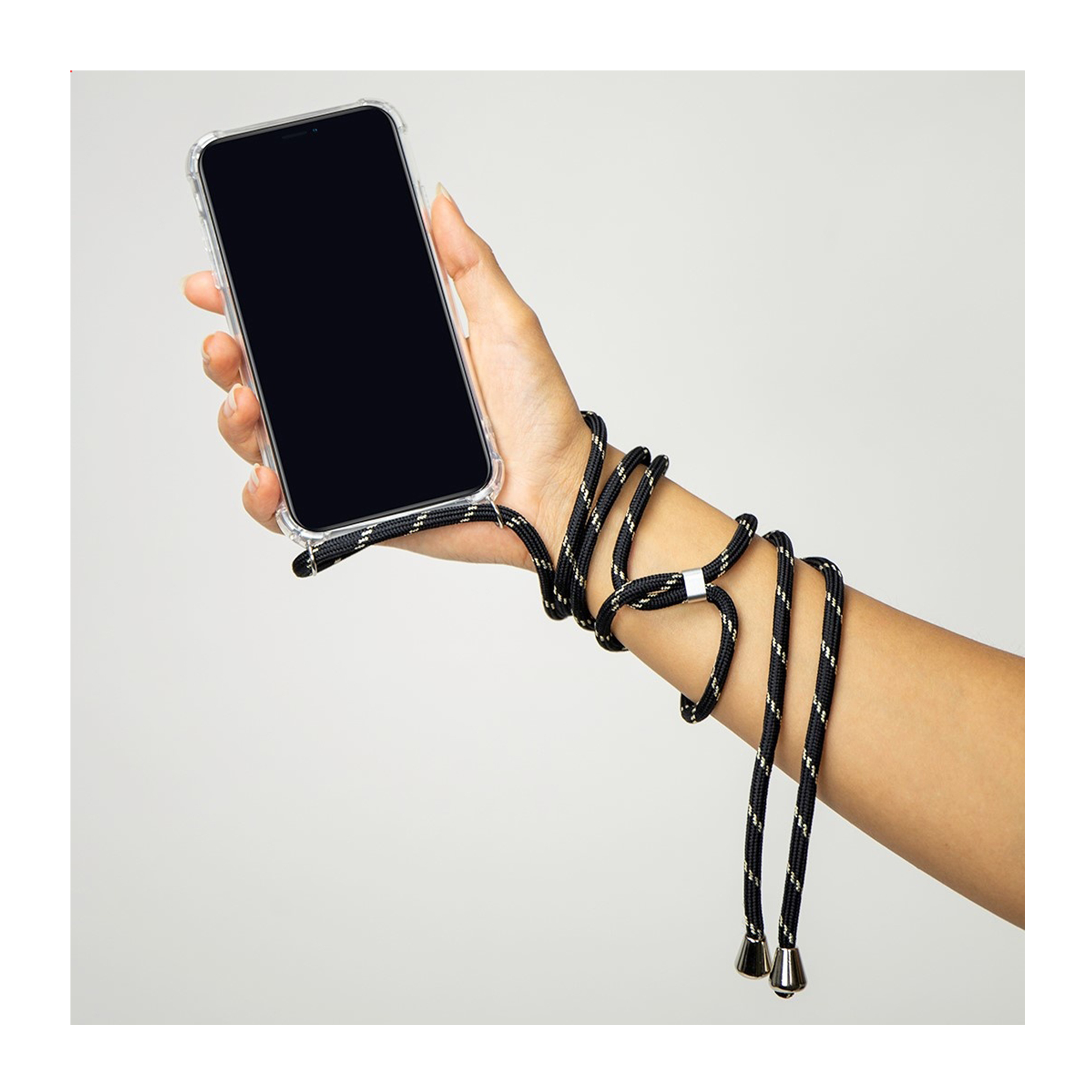 Una mano sostiene un smartphone en funda transparente con un cordón negro enrollado en el brazo.
