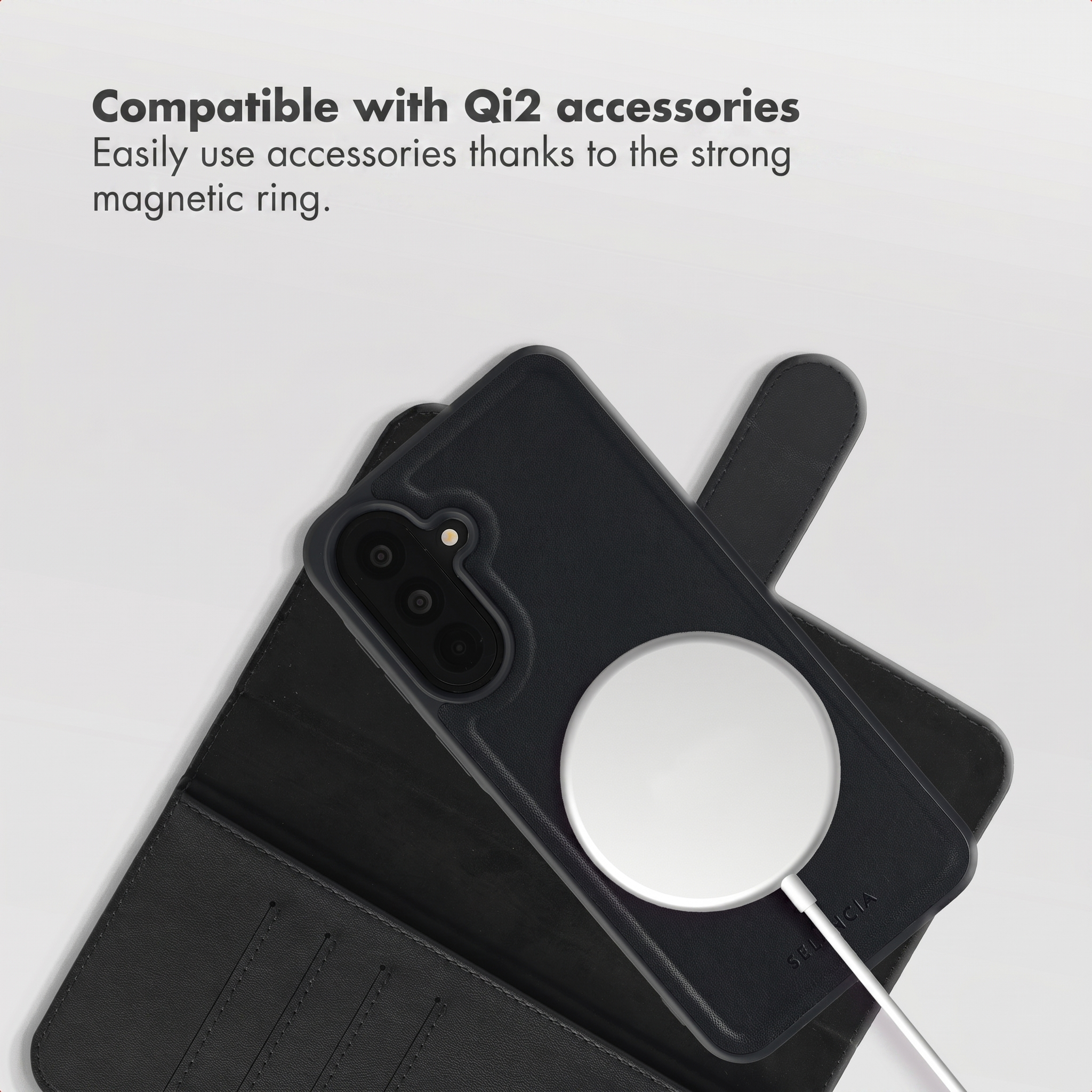 A black phone case with a magnetic wireless charger attached, resting on a matching black leather wallet case.