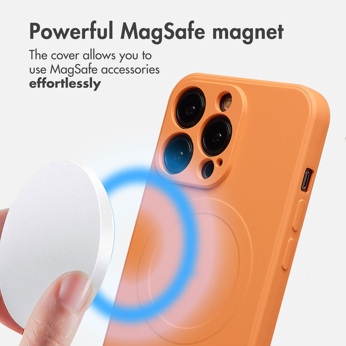 Una mano tiene un magnete MagSafe bianco rotondo vicino a una custodia per telefono arancione con fotocamera.