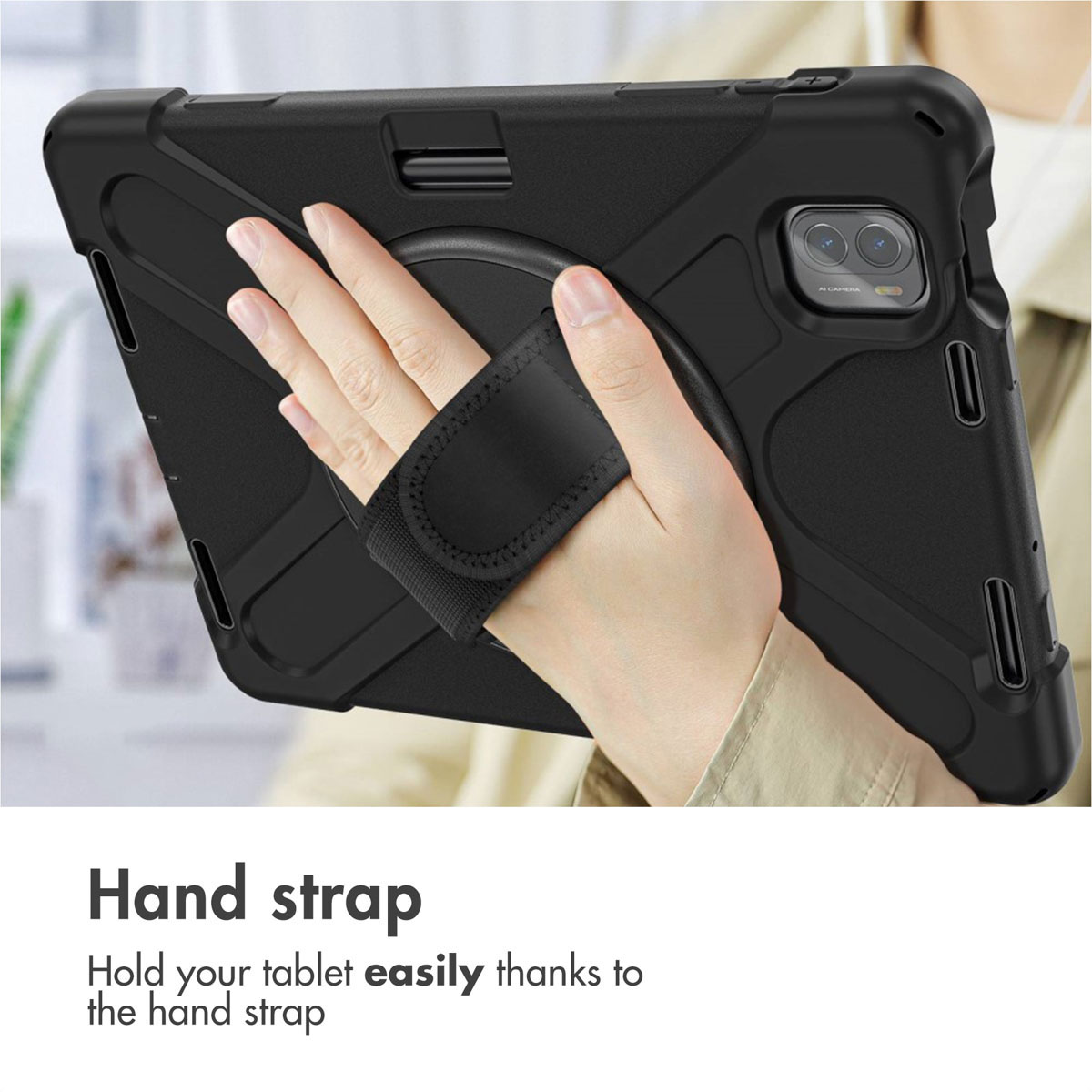 Une main tient une tablette noire dans une coque de protection avec sangle.