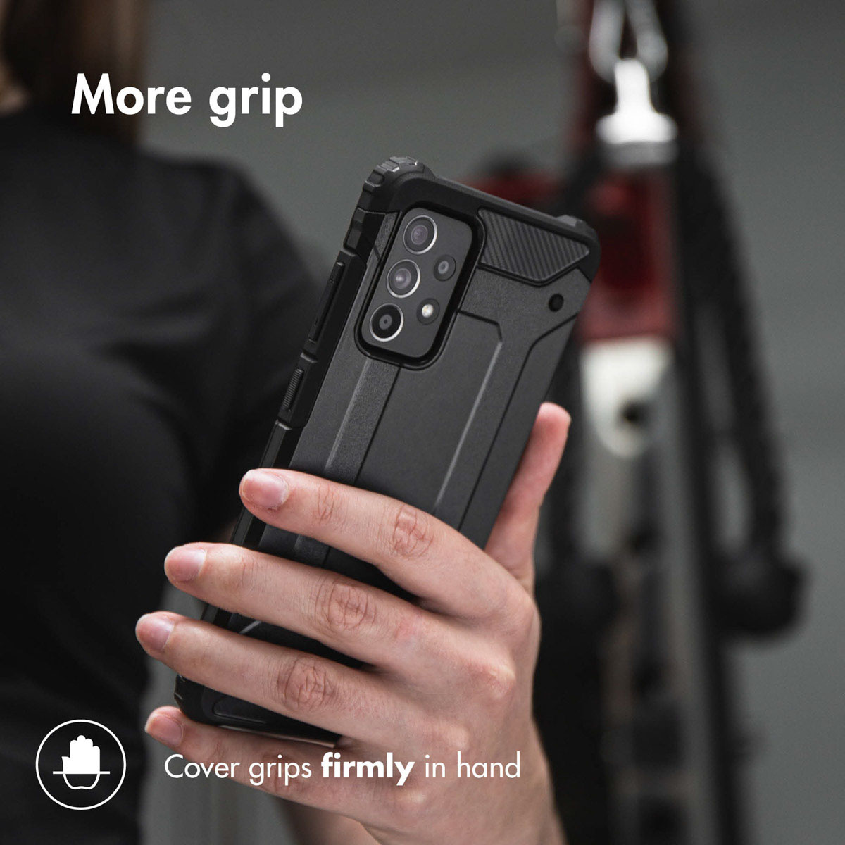 Une main tient un smartphone dans une coque noire robuste, avec du texte.