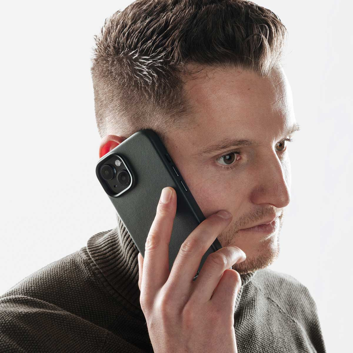 Un uomo con i capelli corti sta telefonando con uno smartphone nero.