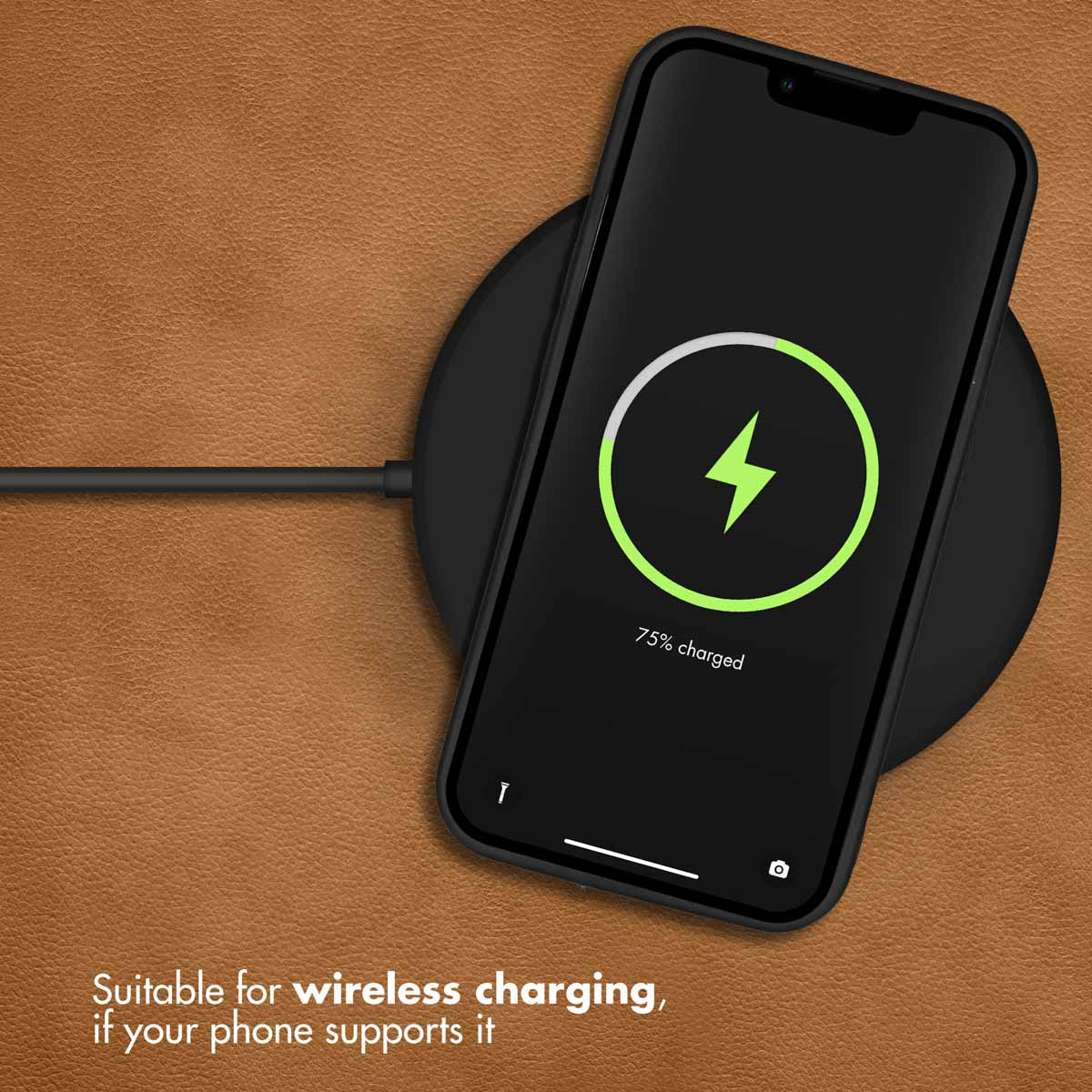Uno smartphone nero si ricarica su un caricabatterie wireless tondo su pelle marrone.