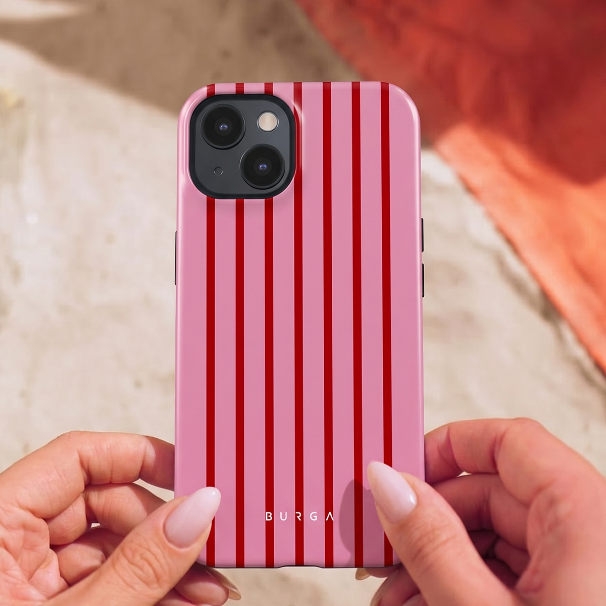 Handen houden een roze hoesje met rode strepen en het Burga-logo vast.