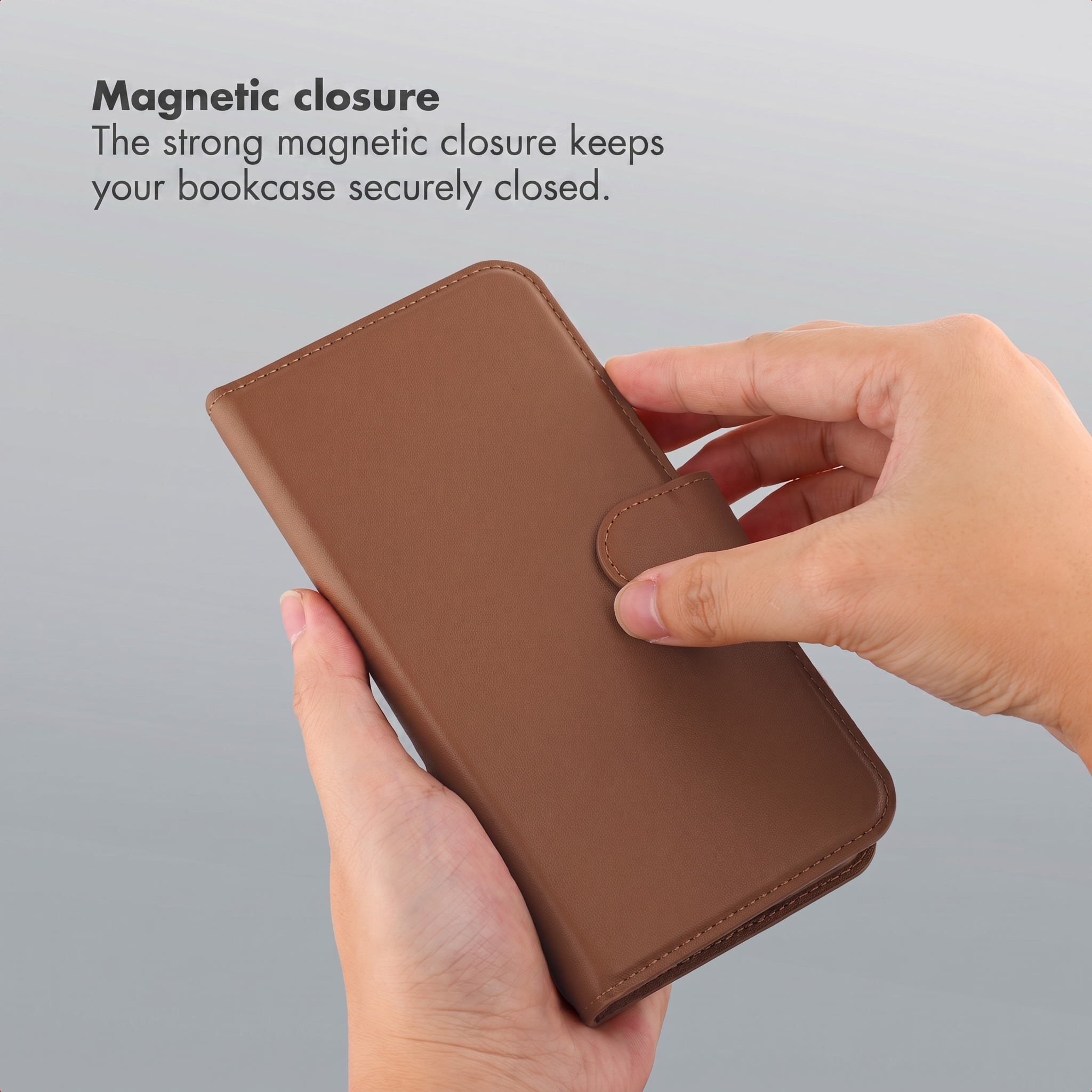 Mains tenant un étui de téléphone en cuir marron avec fermeture magnétique.