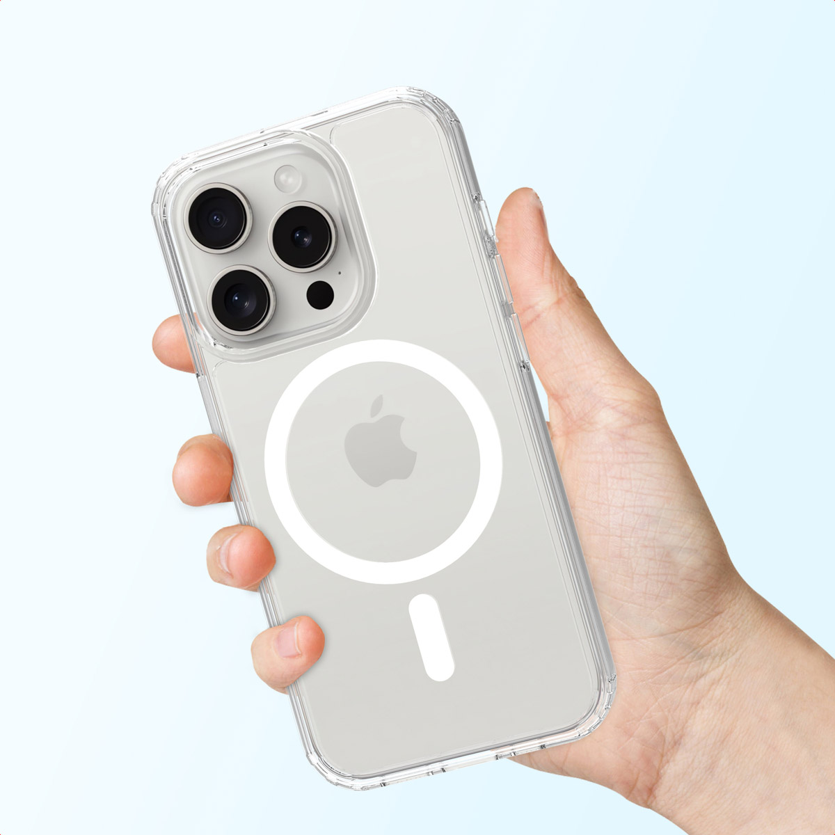 Una mano sostiene un iPhone con funda transparente y anillo MagSafe sobre fondo claro.