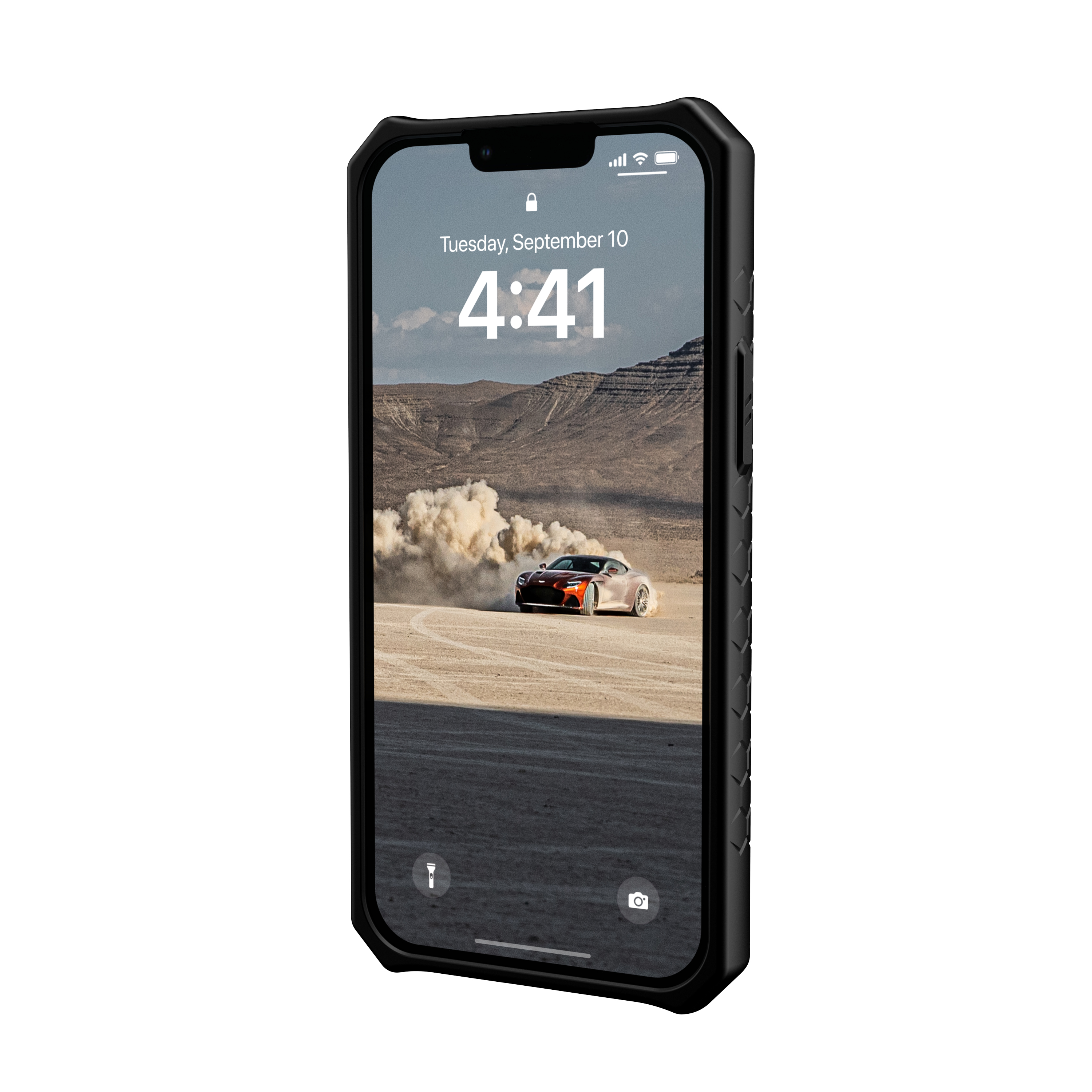 Uno smartphone nero in una custodia robusta mostra lo sfondo di un'auto che solleva polvere nel deserto.