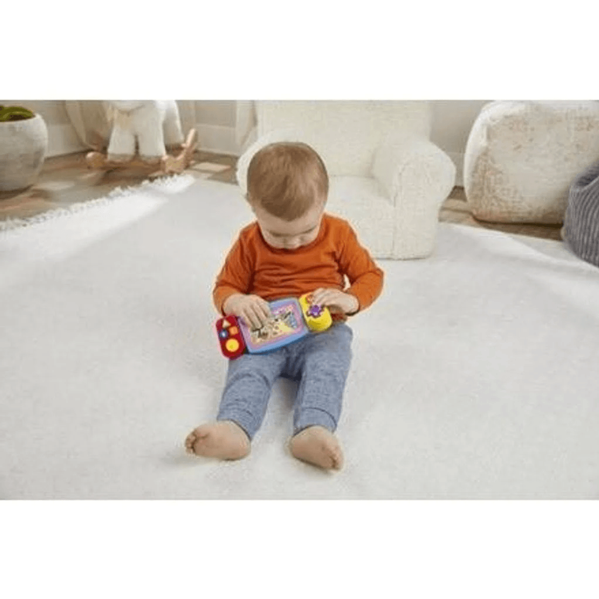Un niño pequeño se sienta en una alfombra blanca jugando con un juguete colorido en una habitación luminosa.