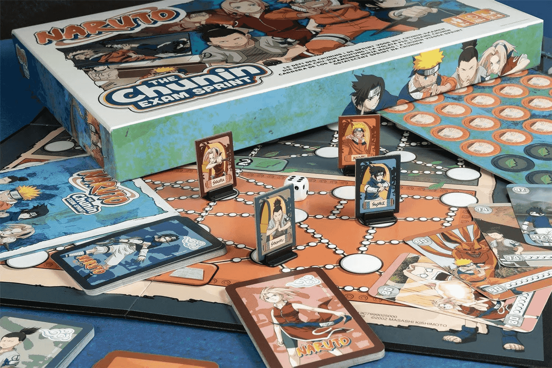 El juego de mesa Naruto The Chunin Exam Sprint con cartas, figuras de personajes y una caja en una mesa.