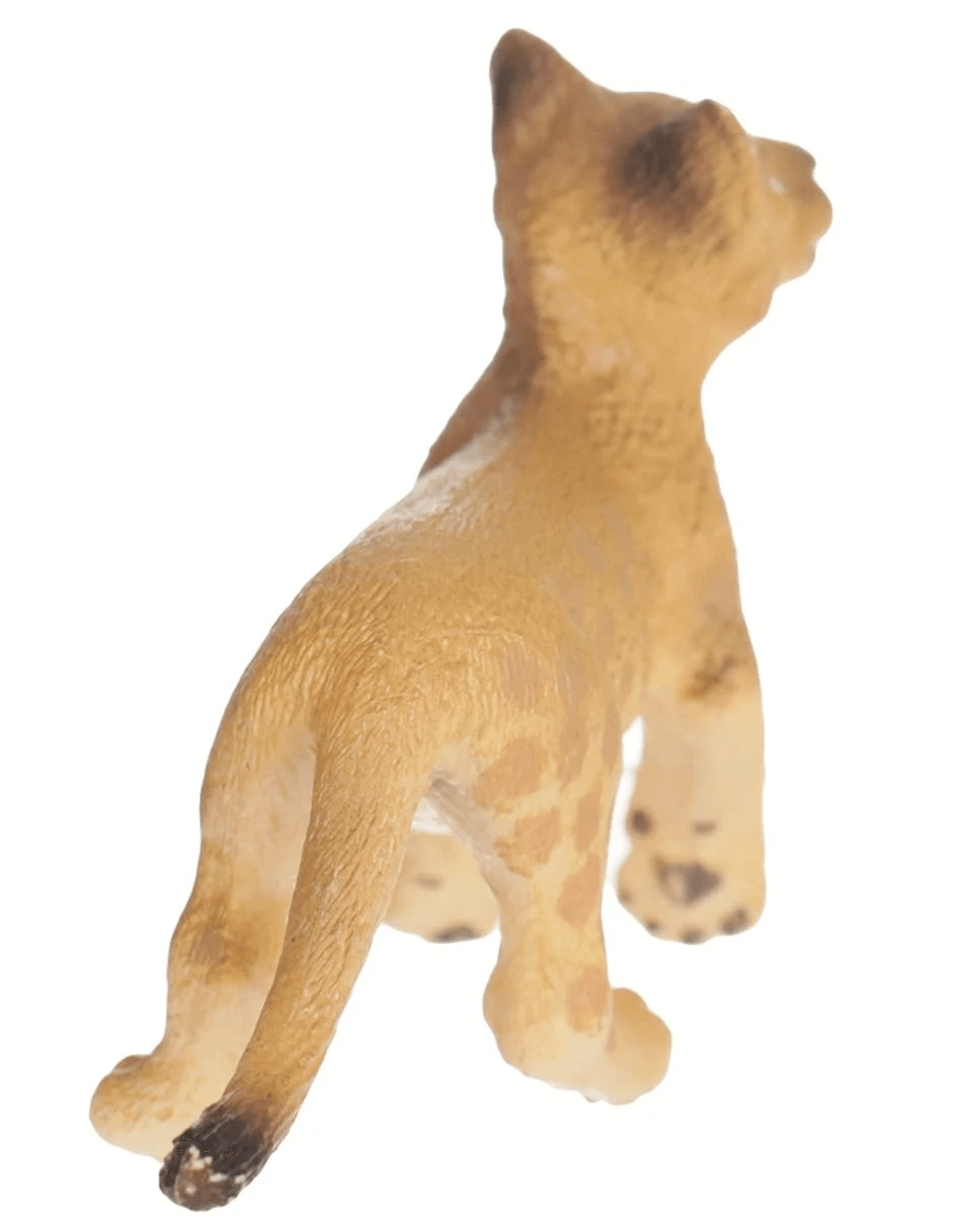 Eine kleine braune Löwenfigur von hinten, die auf einer weißen Oberfläche steht.
