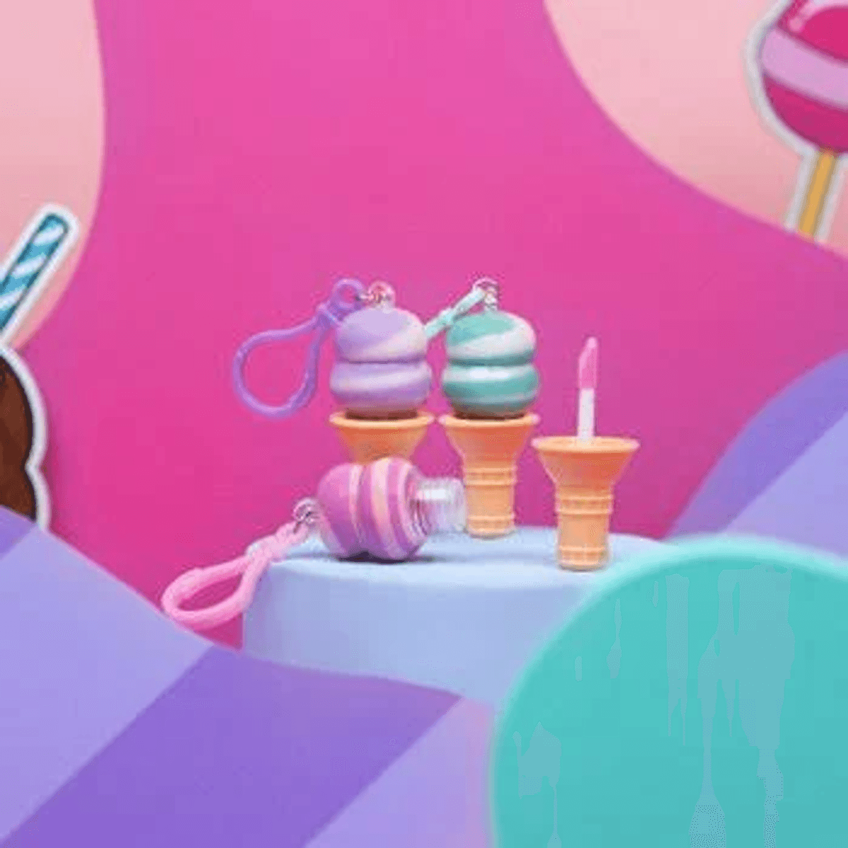 Bálsamos labiales y botes de gel hidroalcohólico con forma de helado sobre un pedestal rosa.