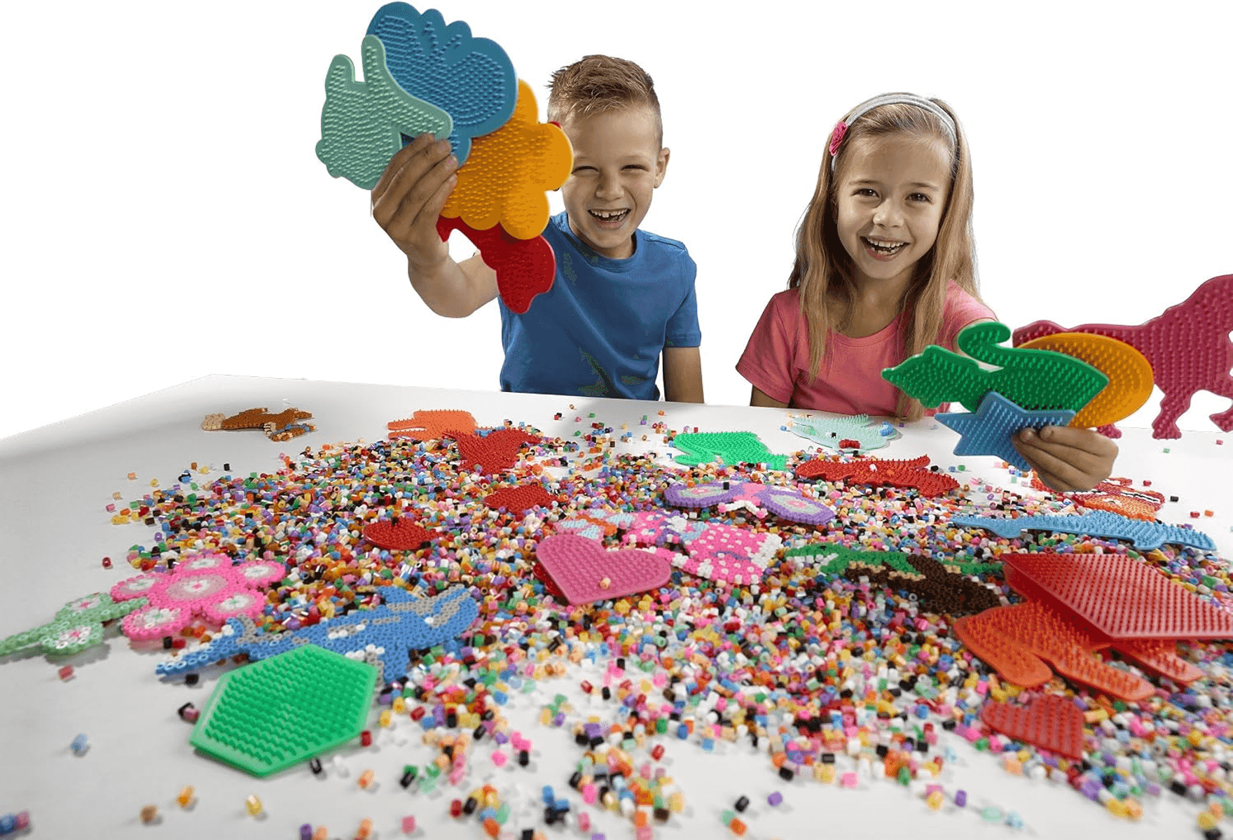 Niños felices jugando con cuentas coloridas y plantillas en una mesa.