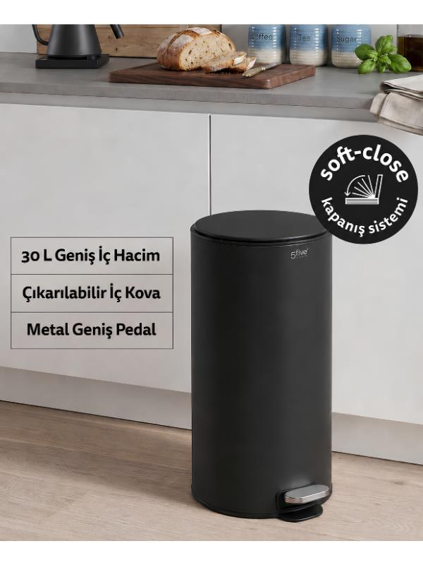 Beyaz dolapların önündeki bir mutfakta siyah silindirik bir pedal kutusu duruyor.