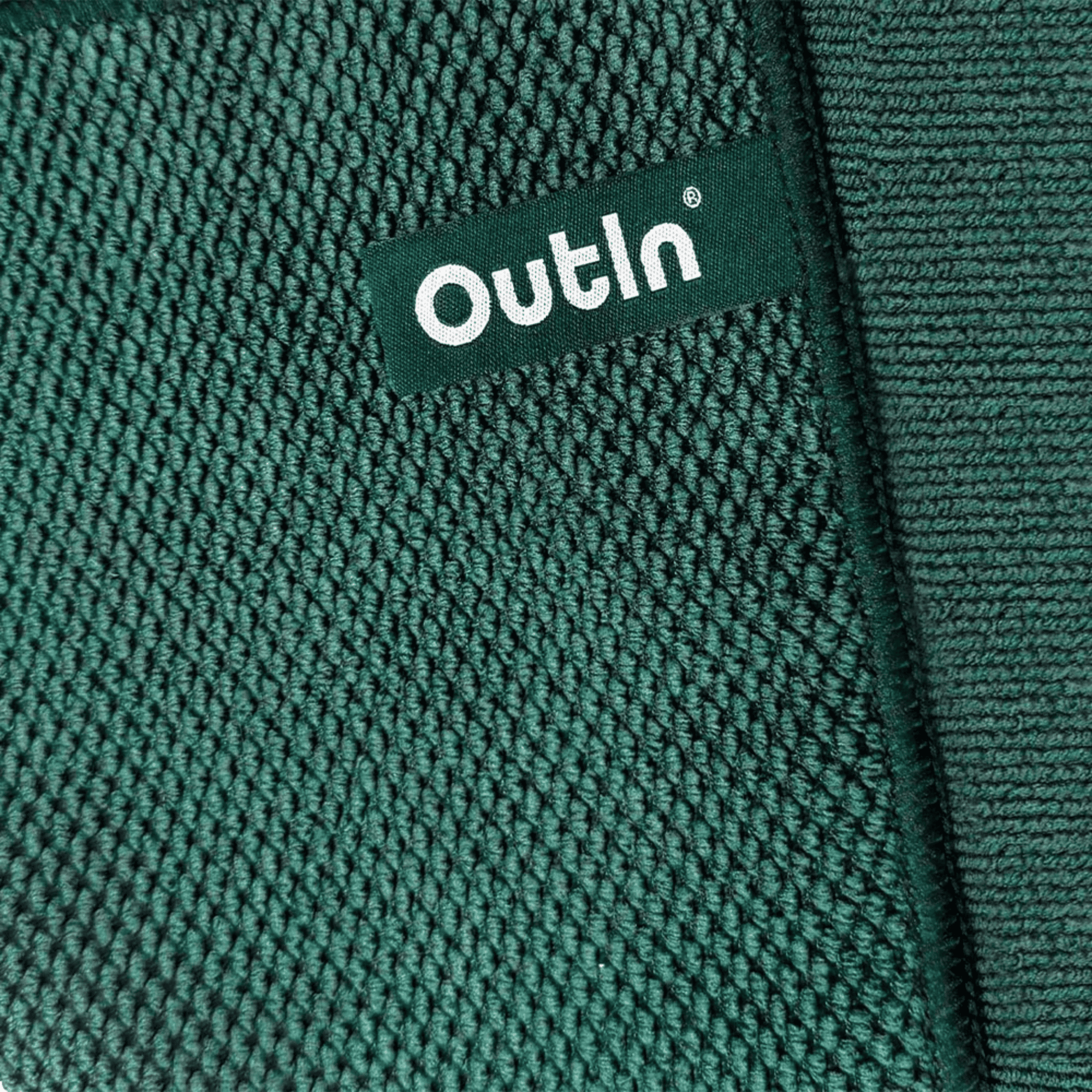 Nahaufnahme eines dunkelgrünen, strukturierten Mikrofaserhandtuchs mit weißem Outin-Etikett.