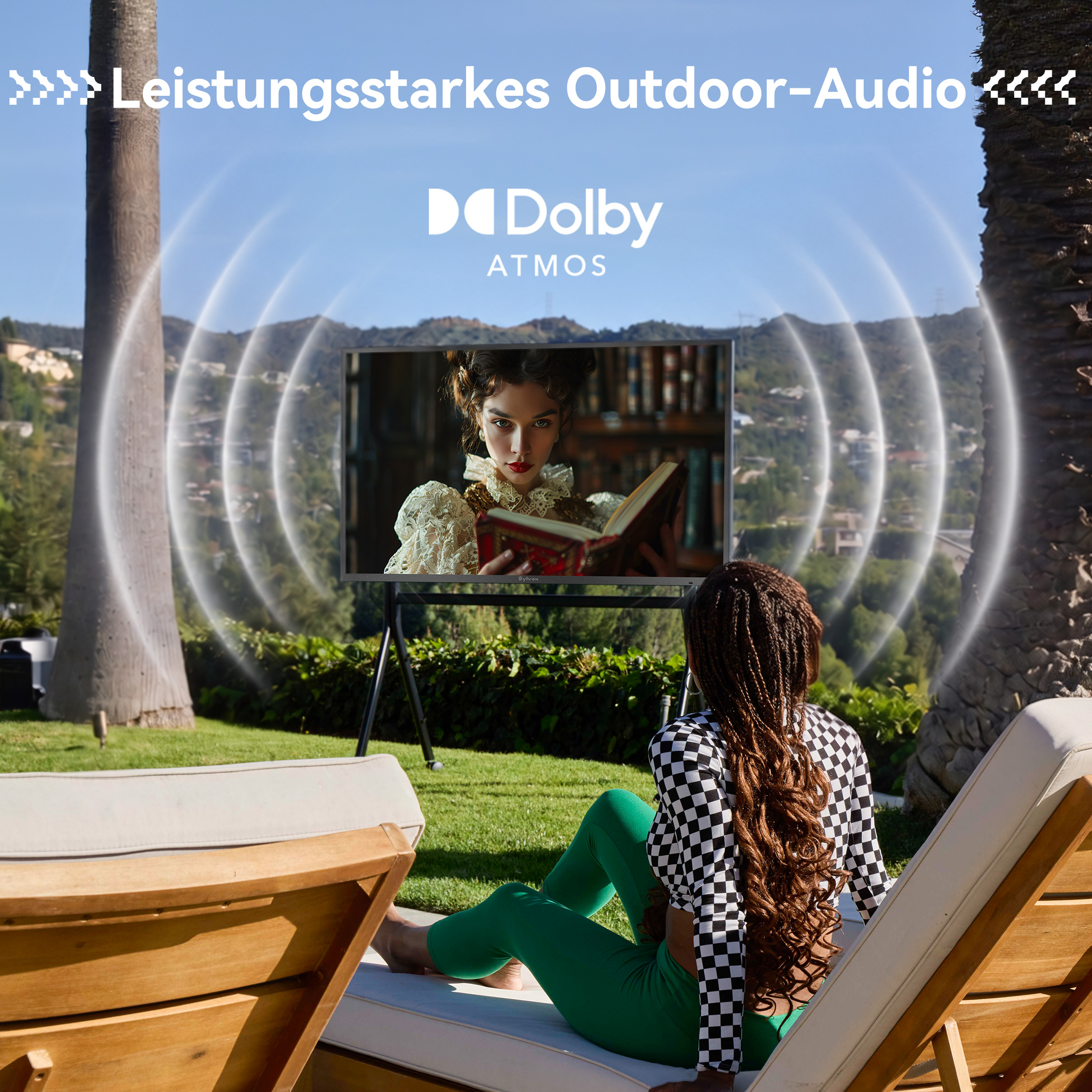 Mujer relajándose en una tumbona al aire libre viendo la televisión con sonido Dolby Atmos.