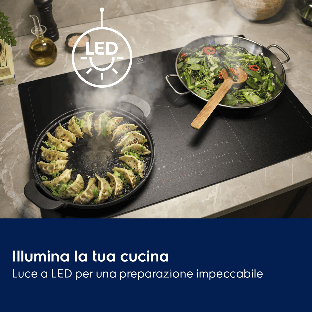 Una placa de inducción negra con dos sartenes cocinando, un icono de luz LED brillante y texto promocional en italiano.