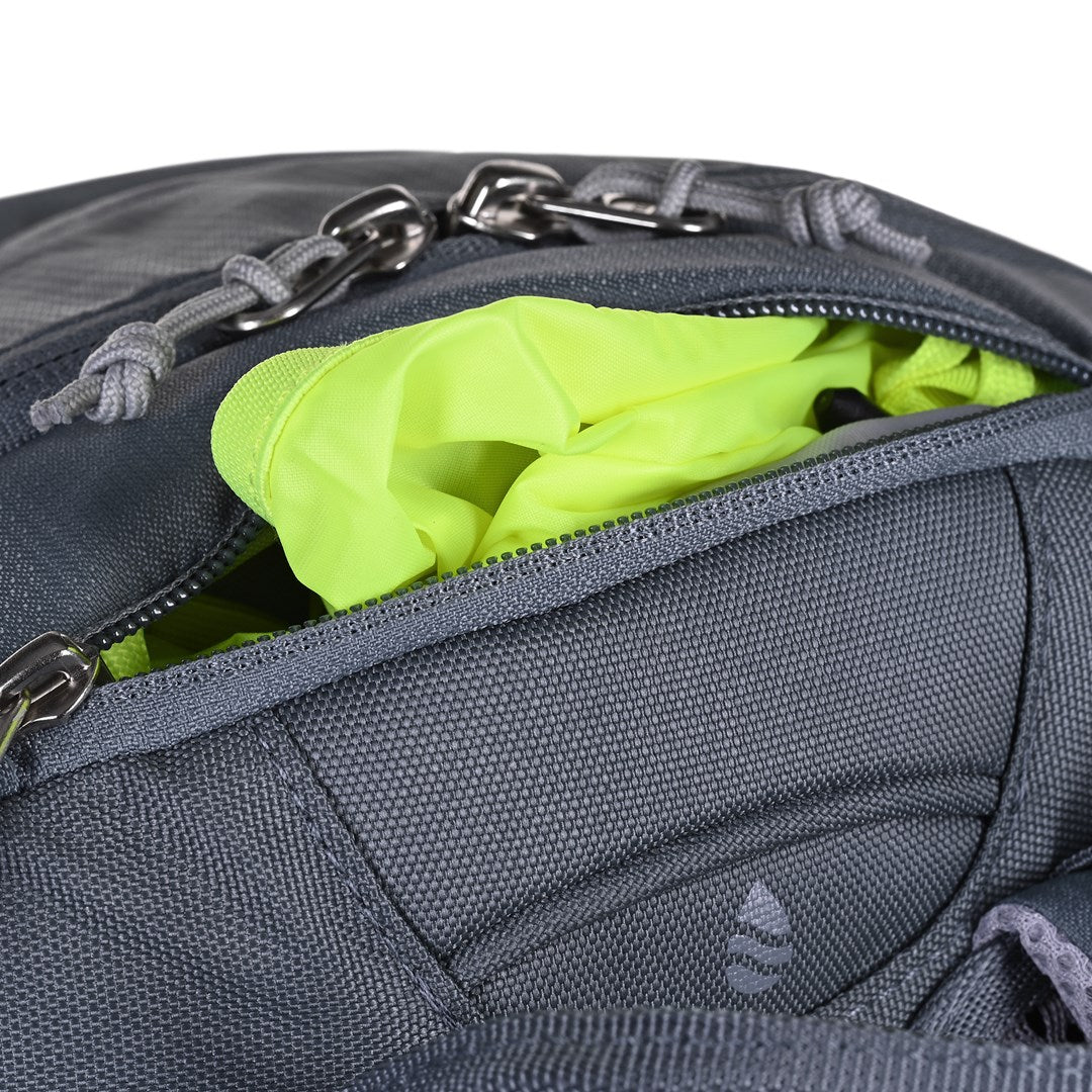 Nahaufnahme eines grauen Rucksacks mit offener Tasche, aus der leuchtend gelber Stoff herausschaut.