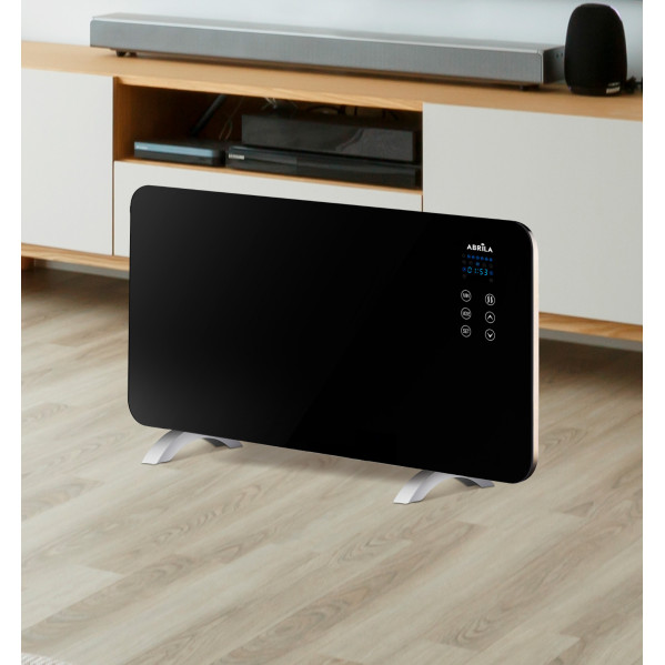 Un calefactor negro con soporte blanco sobre un suelo de madera frente a un mueble de TV.