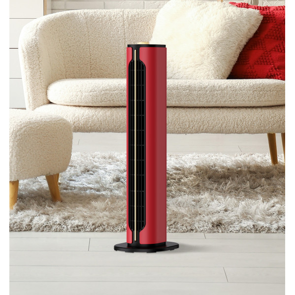 Un ventilador de torre rojo y negro sobre suelo de madera clara frente a un sofá blanco.