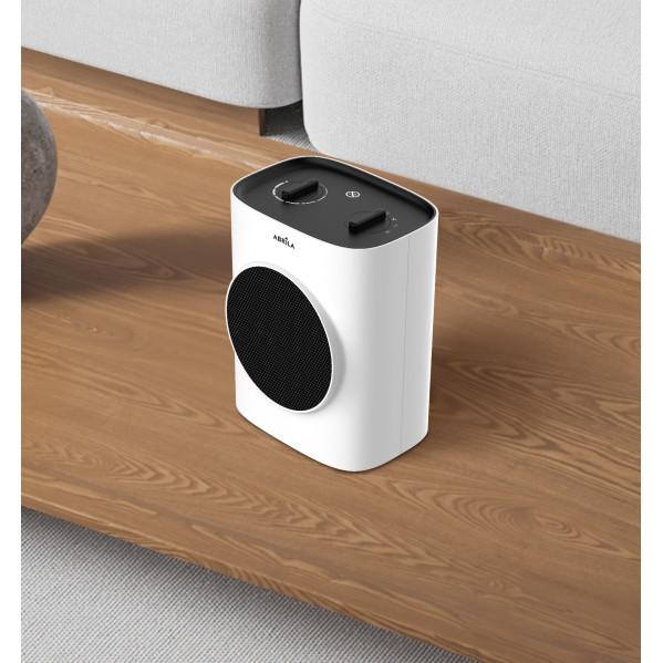 Un calefactor compacto blanco con rejilla y controles negros sobre una mesa de madera frente a un sofá.