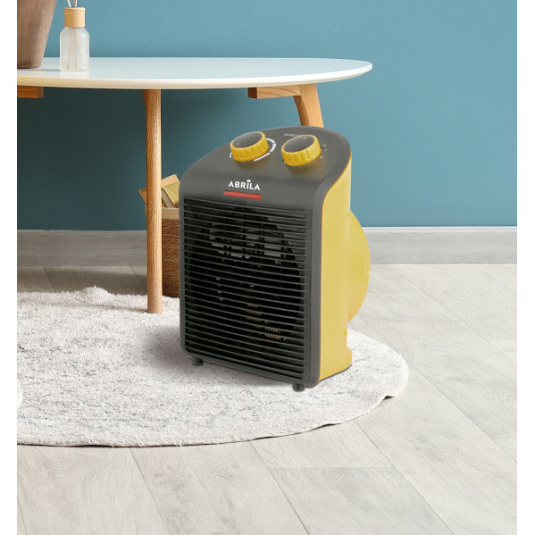 Un calefactor eléctrico amarillo y negro sobre una alfombra blanca y esponjosa en el suelo.