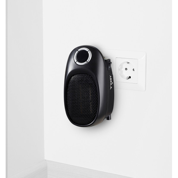 Un mini calefactor negro está enchufado en una toma de corriente sobre fondo blanco.