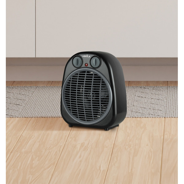 Un calefactor eléctrico negro con perillas grises sobre piso de madera.