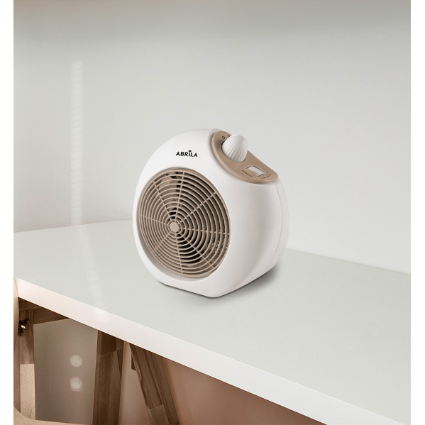 Un calefactor compacto blanco con detalles en beige sobre una mesa blanca ante una pared clara.