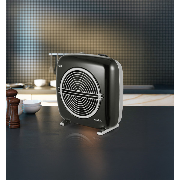 Un calefactor de aire retro negro se encuentra en una encimera oscura frente a una cocina moderna.