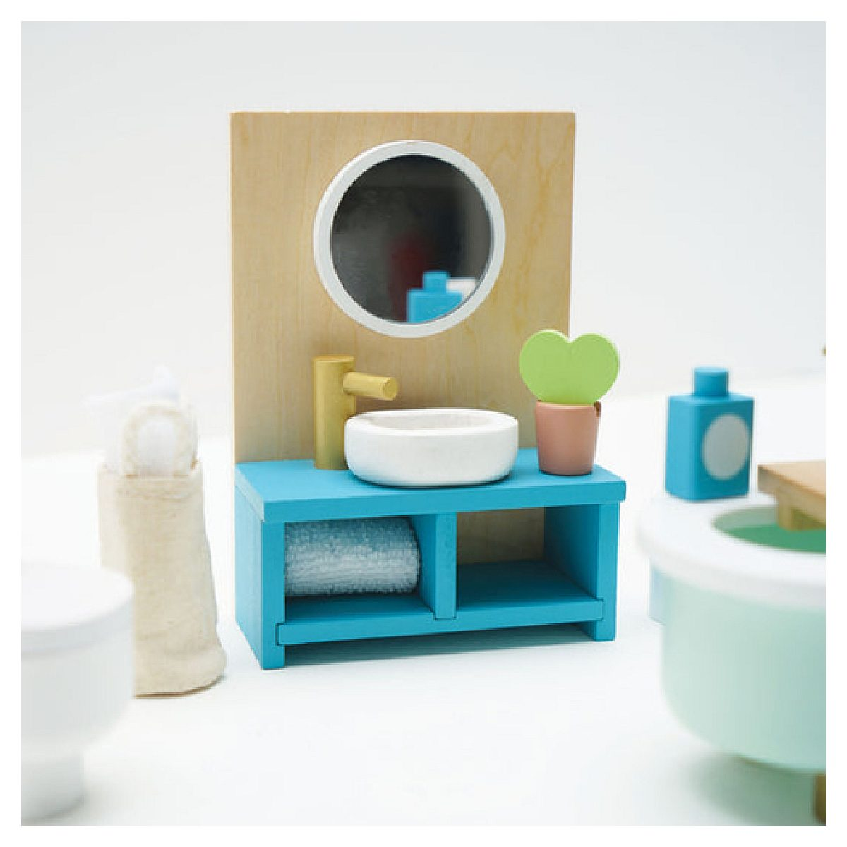 Un mobile da bagno in miniatura in legno blu brillante con specchio rotondo, rubinetto dorato e piccola pianta.