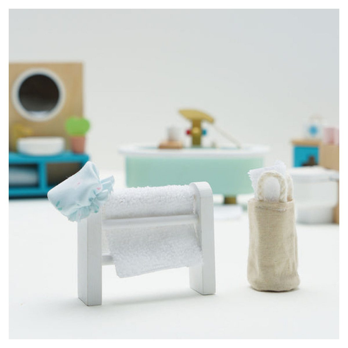 Bagno in miniatura in legno con portasciugamani bianco, sacco portabiancheria e vasca.