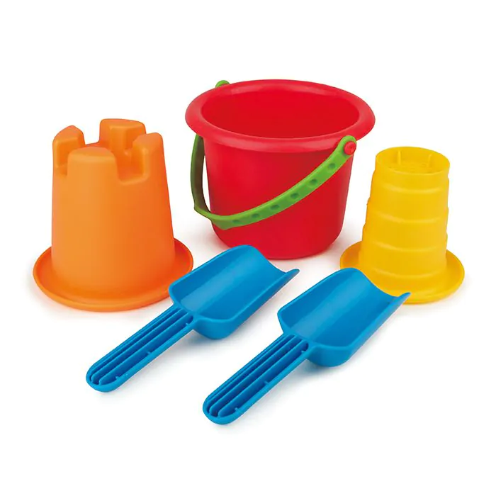 Jouets de plage colorés : seau rouge, moules orange et jaune, et deux pelles bleues sur fond blanc.